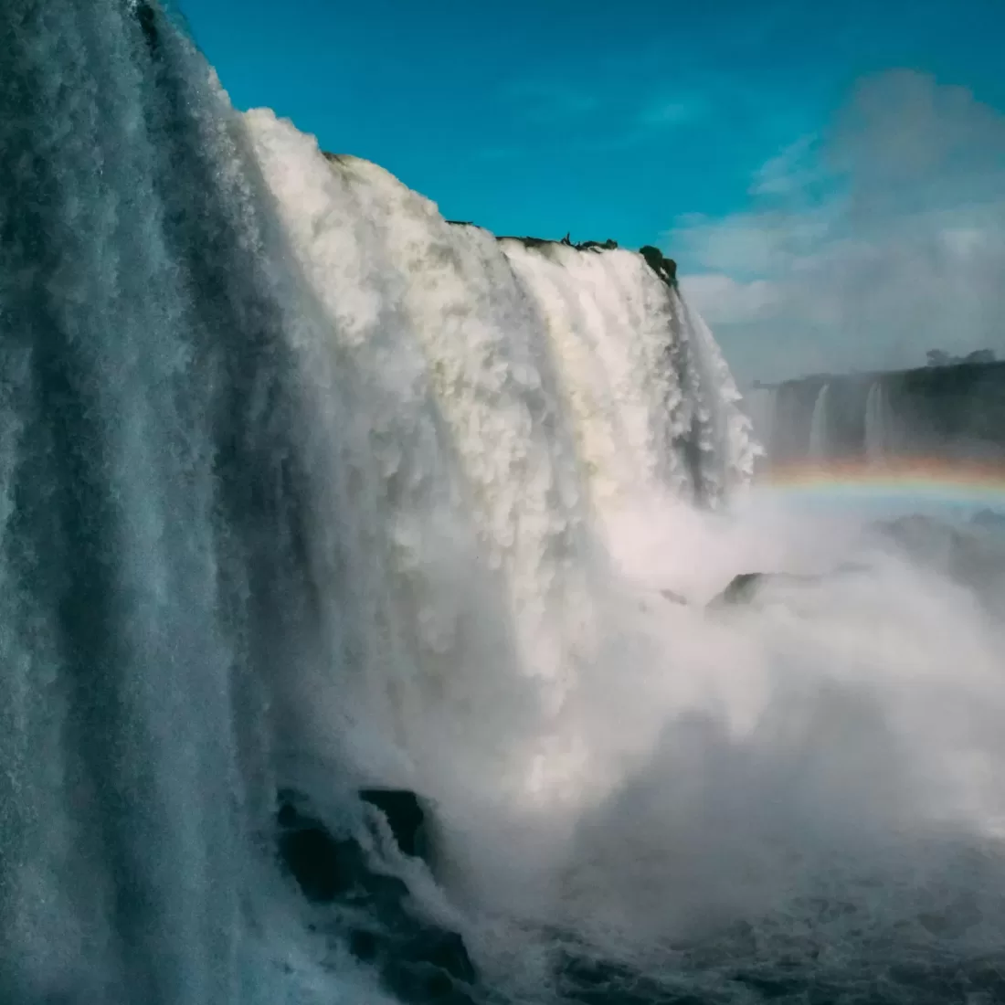Majestic view of Iguazu Falls in Brazil showcasing a vibrant rainbow over cascading waters.