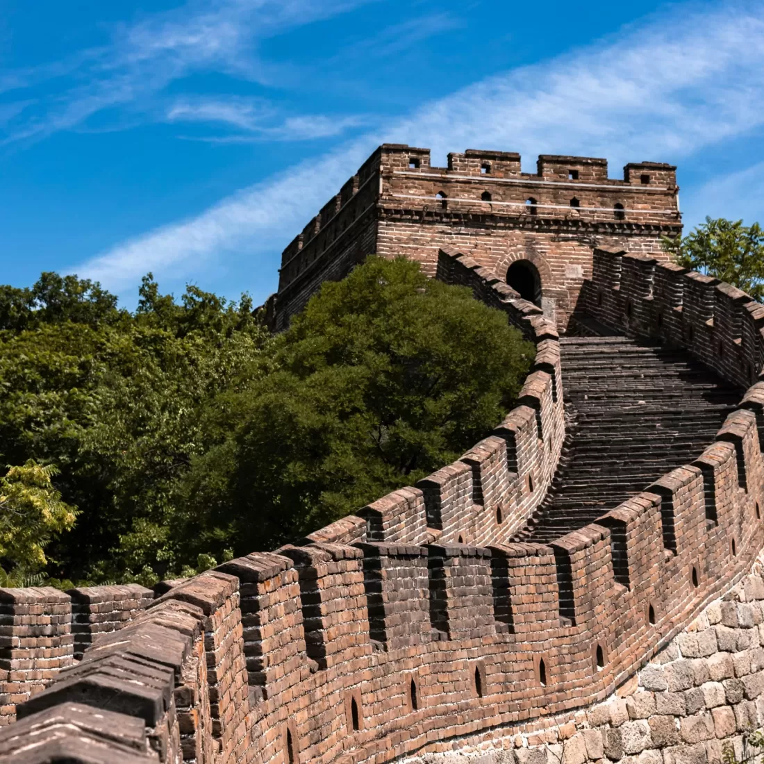 The Great Wall of China surrounded by lush greenery under a clear blue sky.