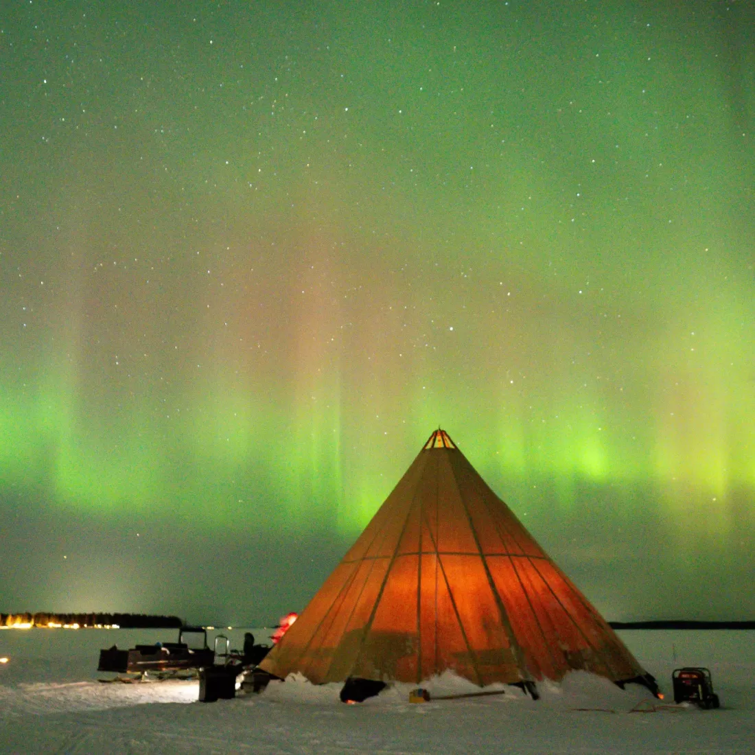 A stunning view of the Northern Lights over a tent in snowy Luleå, Sweden, beautifully captured at night.
