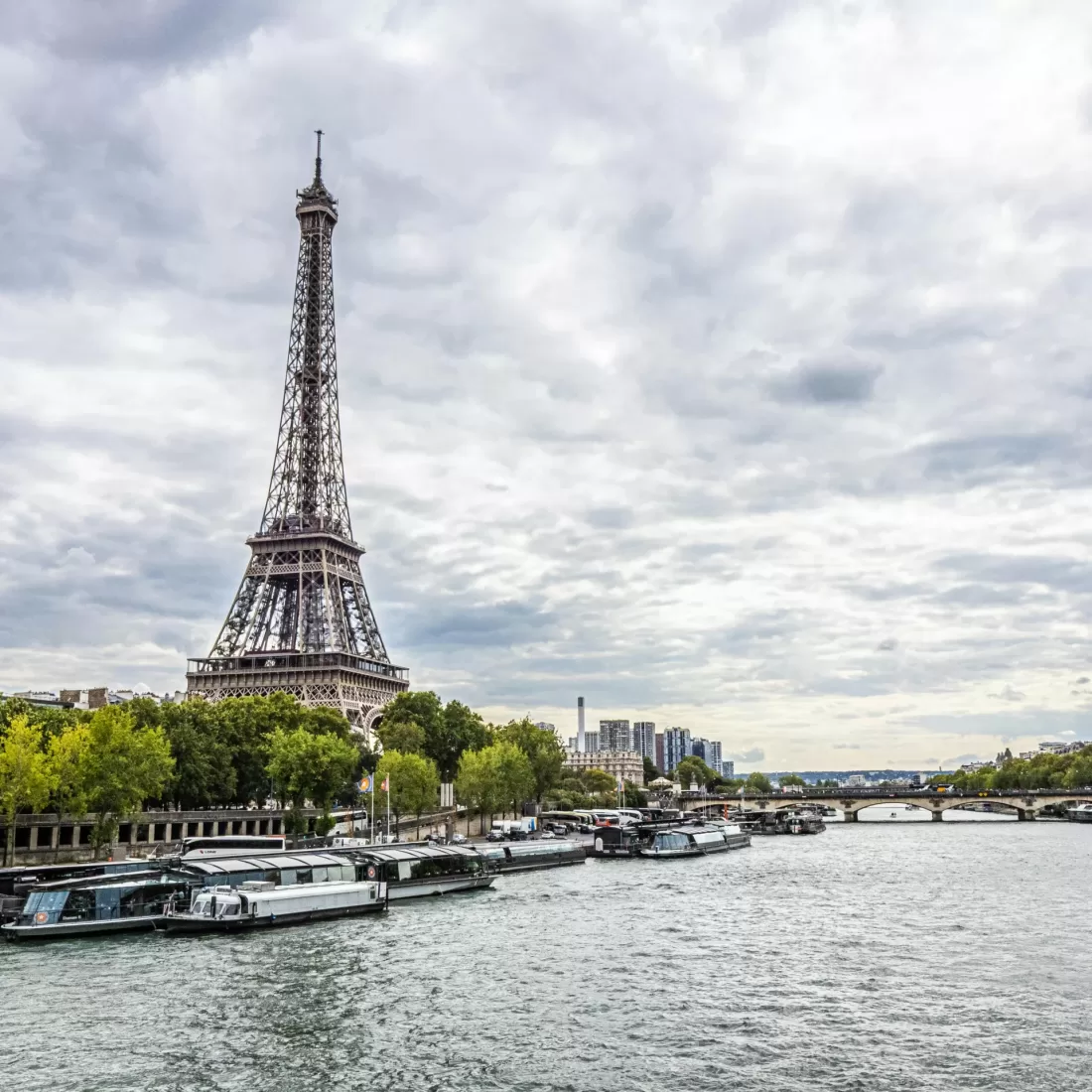 Scenic view of the Eiffel Tower by the Seine River under a cloudy sky in Paris, France.