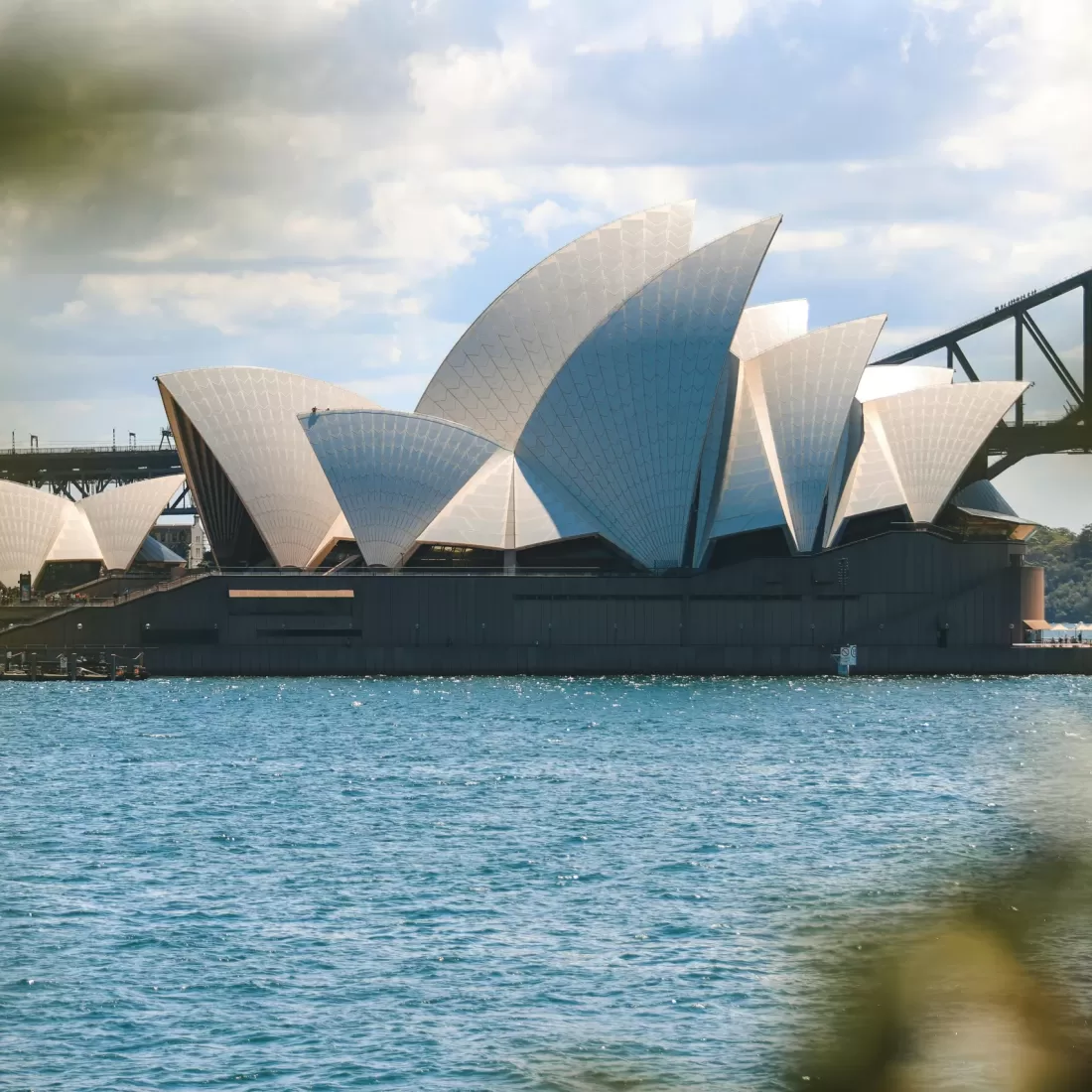 Iconic view of the Sydney Opera House and Sydney Harbor Bridge on a sunny day.